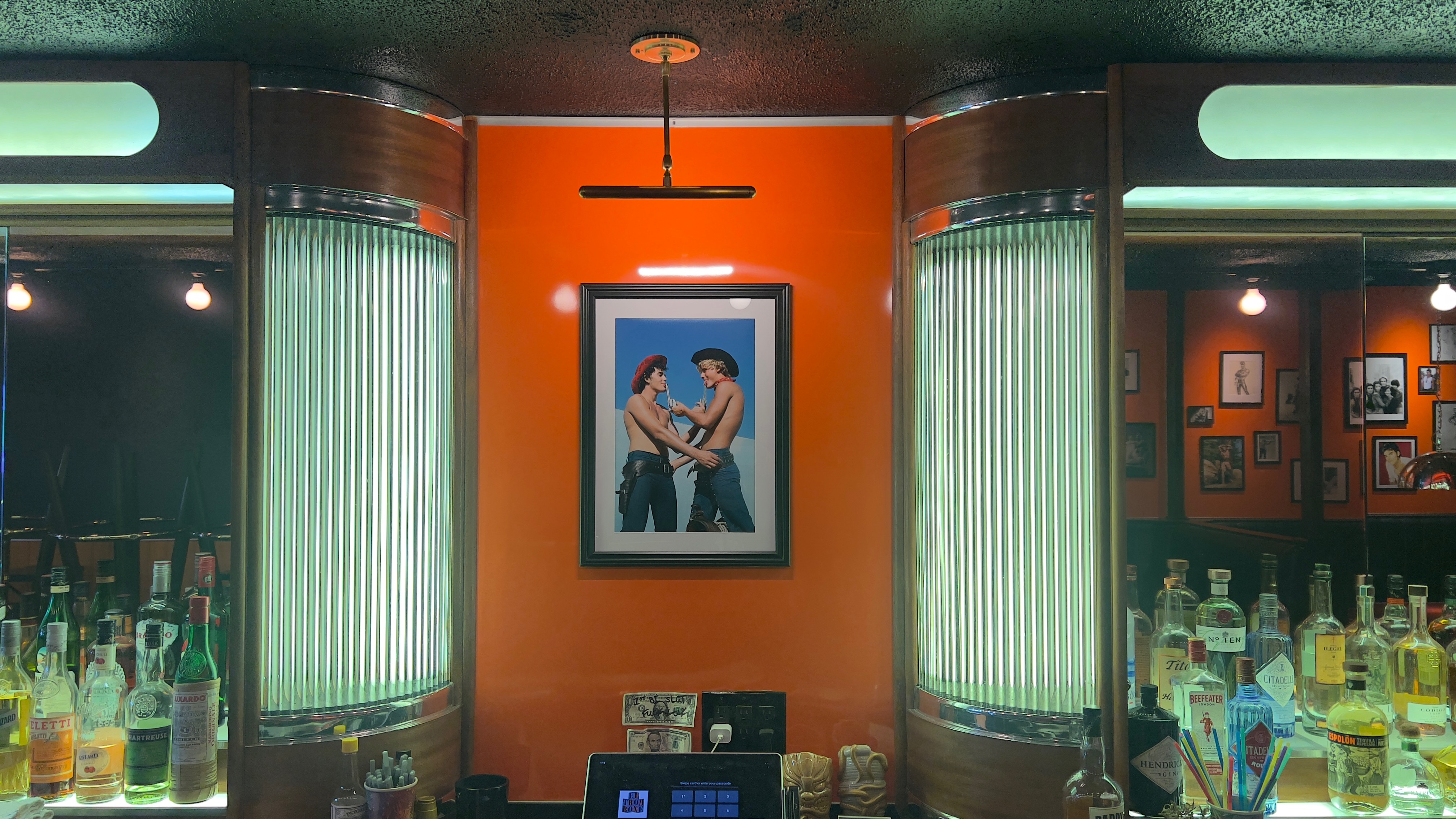 The back bar at El Trombone, bottles lit warm against the wall